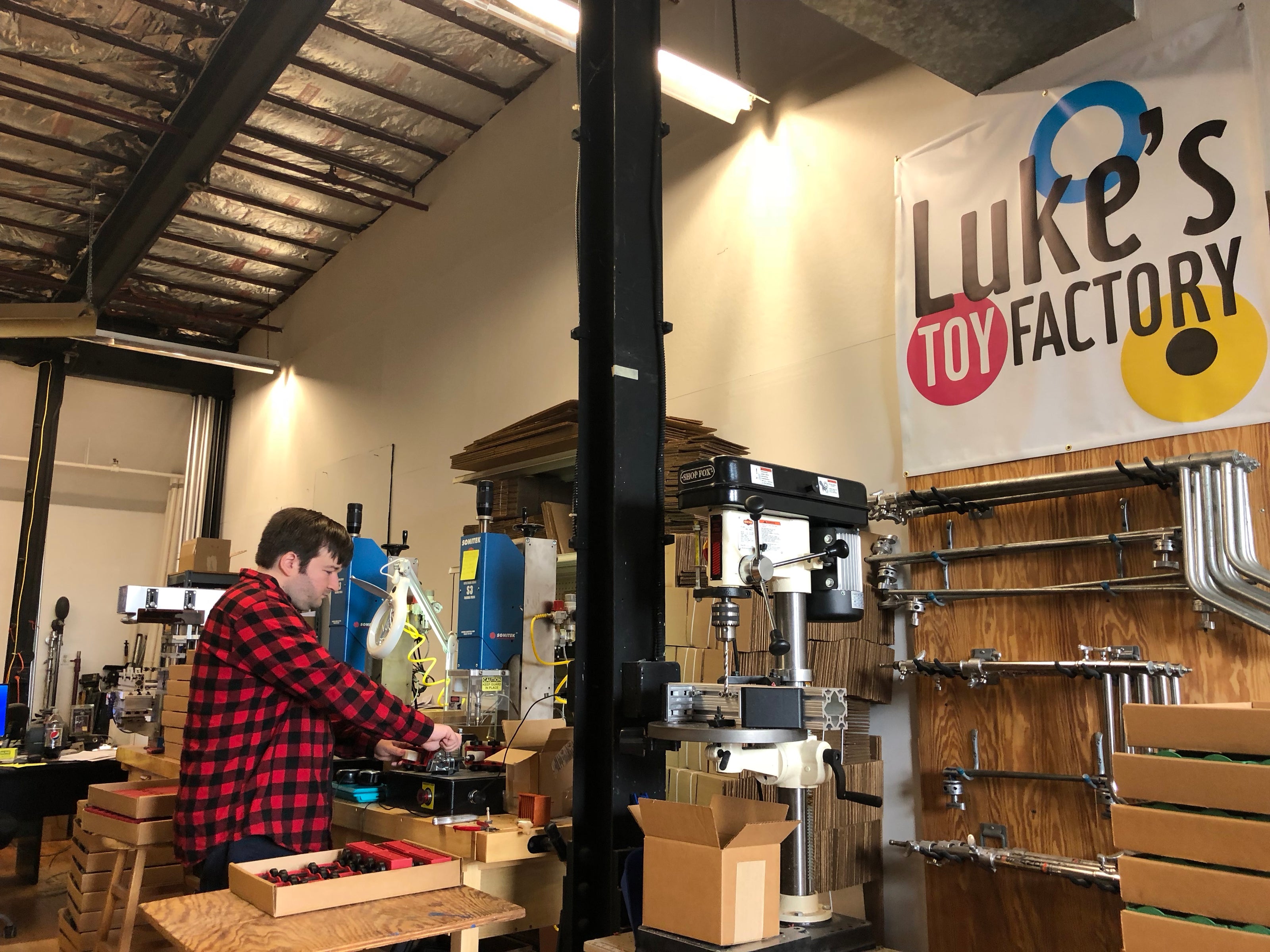 Luke working in the Luke's Toy Factory shop at the heat staking machine, assembling toy trucks