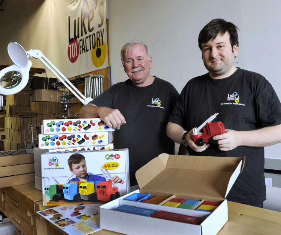 A picture of Luke and his dad Jim showing their truck toys at the toy factory in Danbury, Connecticut