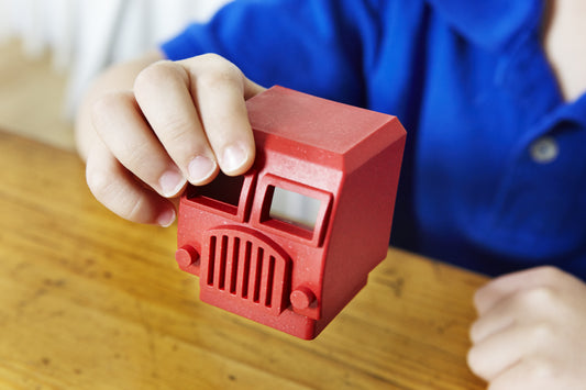 A three year old child hold a red part of the Luke's Toy Factory toy firetruck