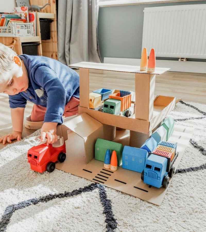 Child Playing with Luke's Toy Factory educational preschool toy trucks in a cardboard house