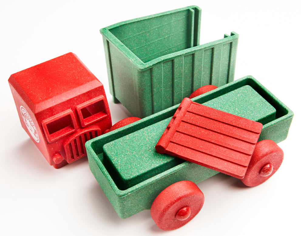 Red and green toy truck with open back on a white background