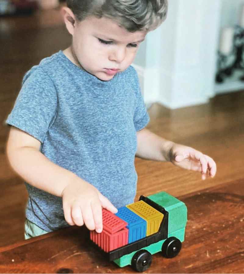 A preschooler plays with an educational toy truck from Luke's Toy Factory